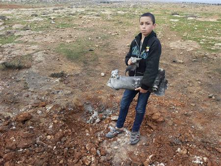 A boy holds the remains of a rocket fired from Syria that hit the Shi'ite town of Hermel January 17, 2014. REUTERS/Rami Bleibel