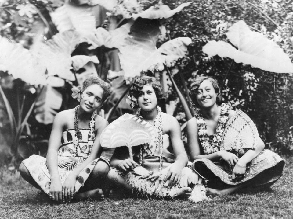 January 1932: A group of Hawaiian girls sitting against a tropical background.