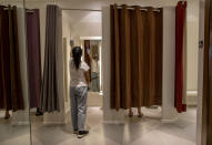 An employee sanitizes a fitting room at the upmarket shopping mall Siam Paragon in Bangkok, Thailand, Sunday, May 17, 2020. Thai authorities allowed department stores, shopping malls and other businesses to reopen from Sunday, selectively easing restrictions meant to combat the coronavirus. (AP Photo/ Gemunu Amarasinghe)