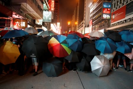 Anti-extradition bill protesters hold umbrellas as they face riot police after a march at Hong Kong’s tourism district Nathan Road near Mongkok