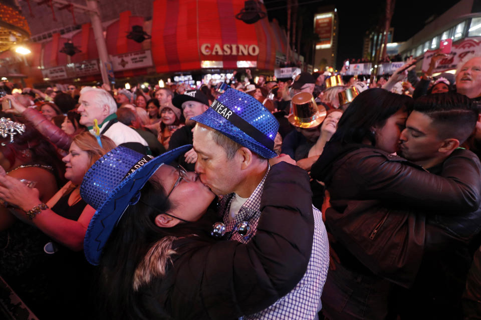 FILE - In this Jan. 1, 2018, file photo, newlyweds Alison and Kenny Finchum, lower left, of Tulsa, Okla., kiss just after midnight during a New Year's party at the Fremont Street Experience in downtown Las Vegas. Plans for a 14,000-person New Year's Eve street party at canopied casino-mall in Las Vegas are facing pushback from state and local officials, who worry Nevada hospitals may not be able to withstand a potential "superspreader" event. (Steve Marcus/Las Vegas Sun via AP, File)