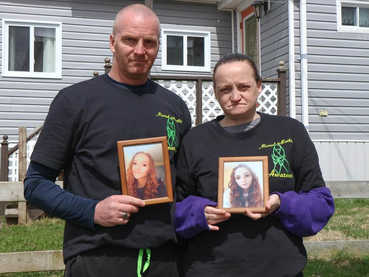William and Penny Molloy hold photos of their daughter, Ashley, outside their home in Harbour Breton. Ashley Molloy died April 11 in hospital in Grand Falls-Windsor, a three-hour drive from Harbour Breton.  (Garrett Barry/CBC - image credit)