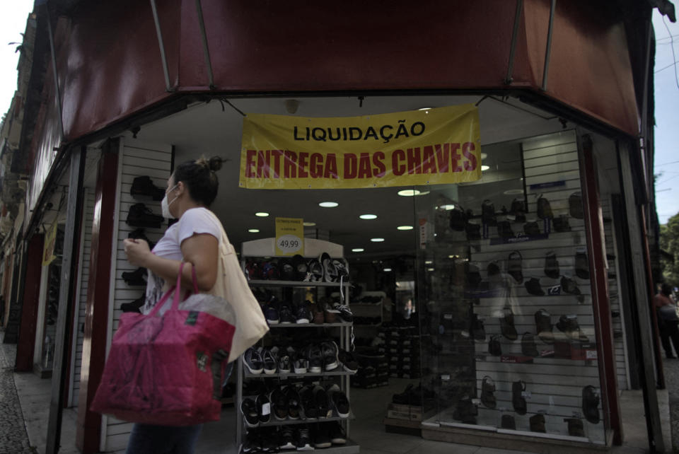 A woman walks past a shoe store reading Sale. Key handover in Rio de Janeiro, Brazil, on December 2, 2021. - Brazil&#39;s economy, the largest in Latin America, slid into recession in the third quarter of 2021 as agricultural production dropped, official data showed Thursday. GDP declined 0.1 percent for the second straight quarterly fall, the government statistics agency IBGE said. (Photo by Mauro Pimentel / AFP) (Photo by MAURO PIMENTEL/AFP via Getty Images)