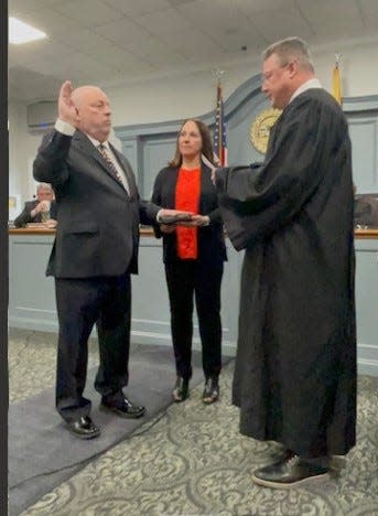 Roger Lane is sworn in by Superior Court Judge Robert Landel as wife Kathy holds the Bible.