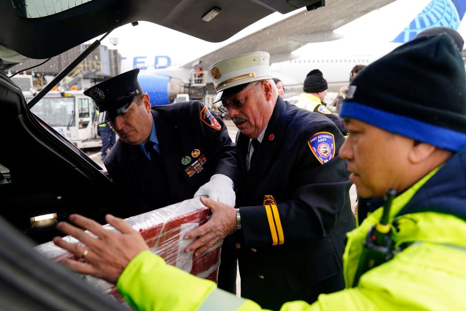 FDNY firefighter Carl Sheetz, left, and Captain Dave Russell of the Port Authority Fire Department (PAFD), center, help prepare the World Trade Center steel, wrapped in an American flag, before it's loaded onto a United Airlines plane heading for London at Newark Liberty International Airport on Tuesday, March 14, 2023. United Airlines, in partnership with the PAFD, transports a piece of the World Trade Center steel to Basildon, England where it will become a part of their September 11 memorial.