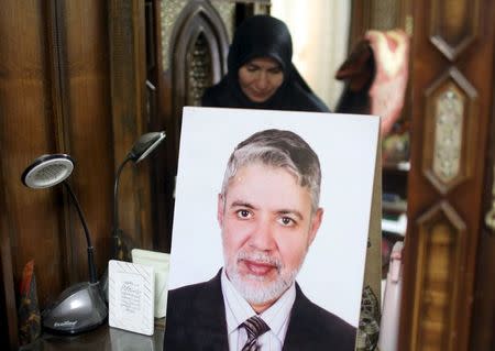 Iman, the wife of Tarek Ghandour is seen reflected in a mirror with a portrait of her husband as she poses for a picture in Cairo, Egypt, July 24, 2015. REUTERS/Asmaa Waguih