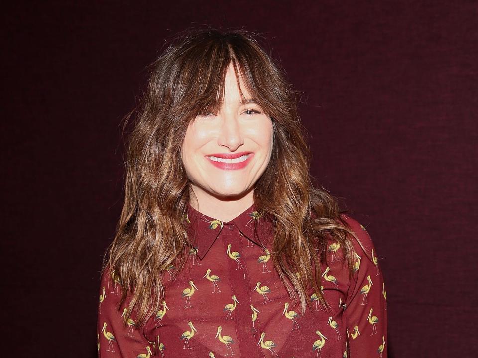 Kathryn Hahn wears a red shirt and smiles