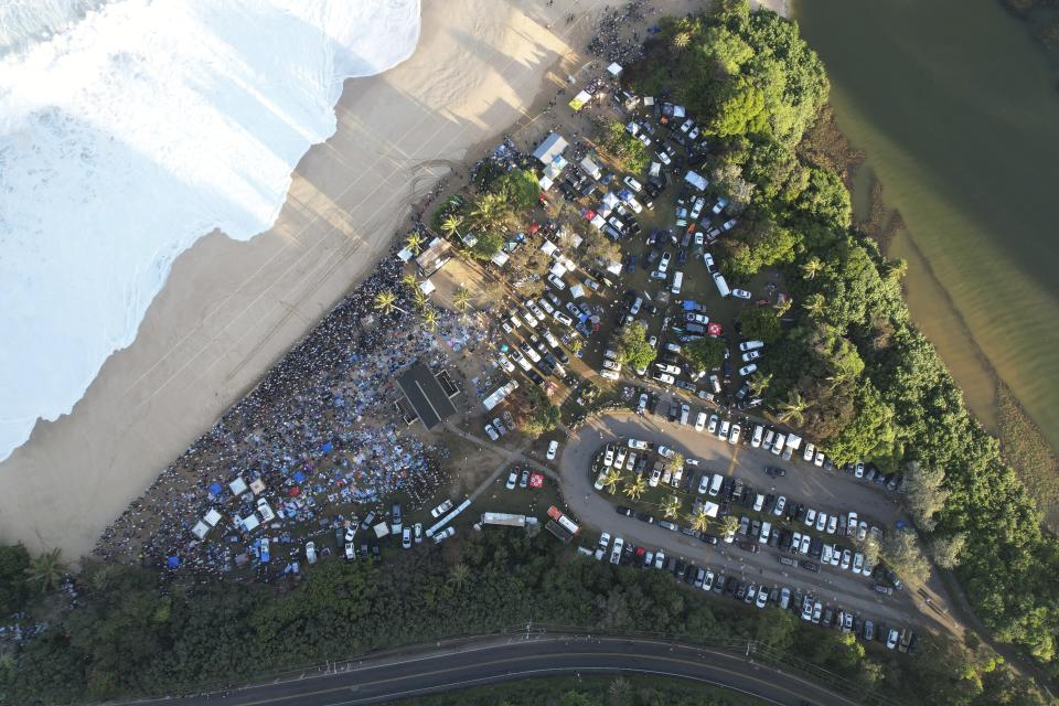 This aerial image provided by Clark Little shows the crowds gathered for the Eddie Aikau Big Wave Invitational surf competition at Waimea Bay, Hawaii, on Oahu’s North Shore, Sunday, Jan. 22, 2023. One of the world’s most prestigious and storied surfing contests is expected to be held Sunday in Hawaii for the first time in seven years. And this year, female surfers will be competing alongside the men for the first time in the 39-year history of The Eddie Aikau Big Wave Invitational. (Clark Little via AP)