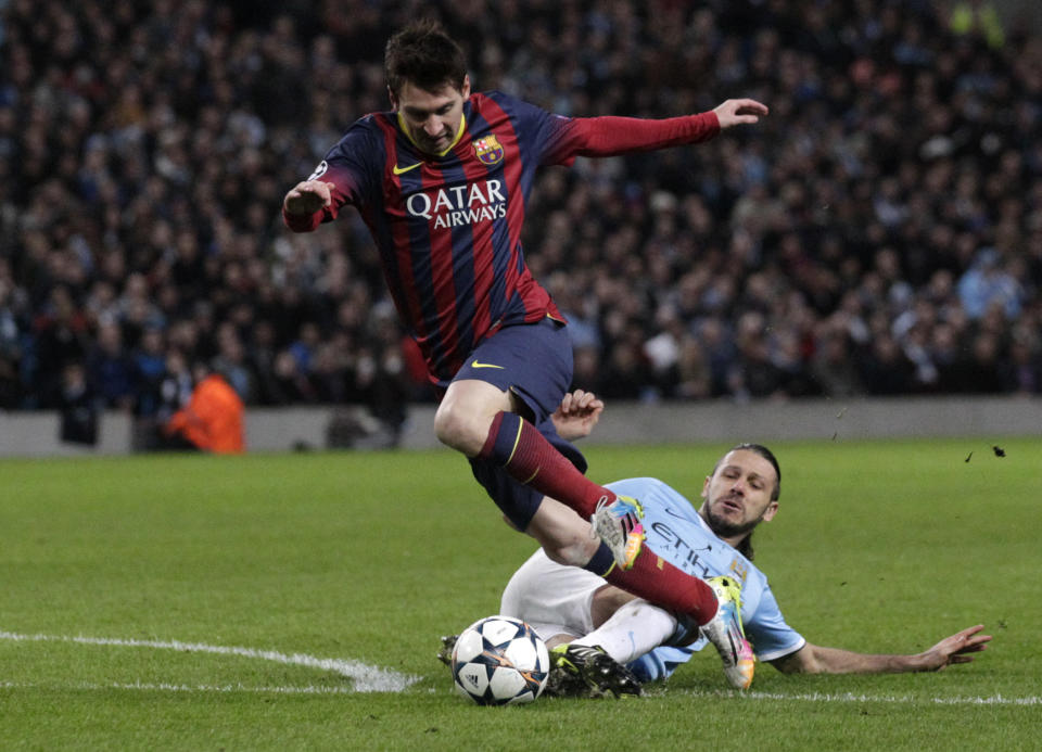 Barcelona's Lionel Messi is tackled down by Manchester City's Martin Demichelis and receives a penalty kick during their Champions League first knock out round soccer match at the Etihad Stadium, Manchester, England, Tuesday Feb. 18, 2014. (AP Photo/Jon Super)