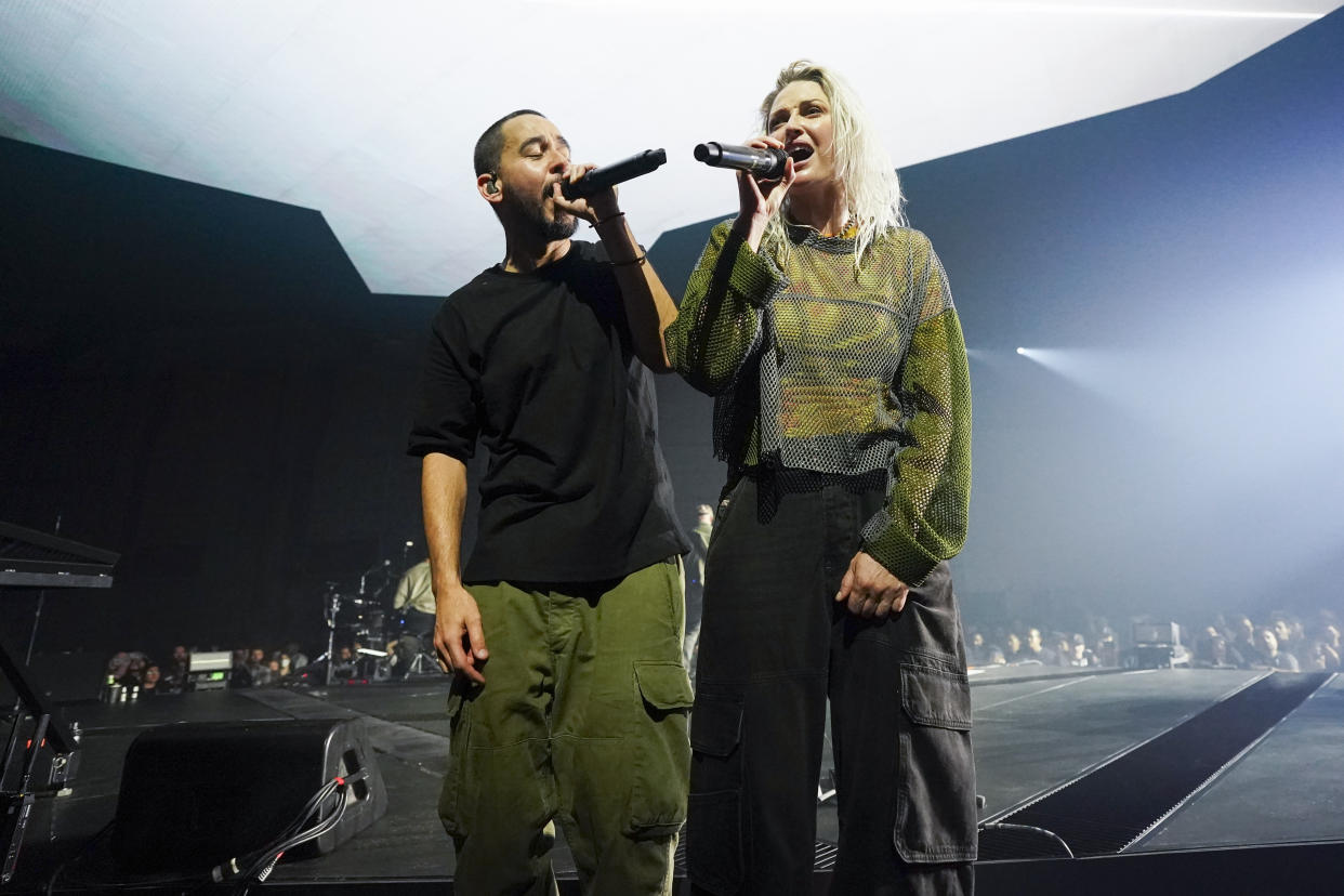 Mike Shinoda and Emily Armstrong stand onstage holding microphones.