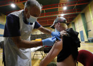 FILE - In this Wednesday, Feb. 3, 2021 file photo, doctor Anil Mehta gives the AstraZeneca vaccine to a homeless person at the homeless accommodation YMCA in Romford, east London. While some non-European Union nations were speeding ahead with emergency use authorizations for vaccines, the EU's drug regulator moved more slowly. The agency's first vaccine greenlight came some three weeks after one was OK'd in the United Kingdom. The bloc never caught up. (AP Photo/Frank Augstein, File)