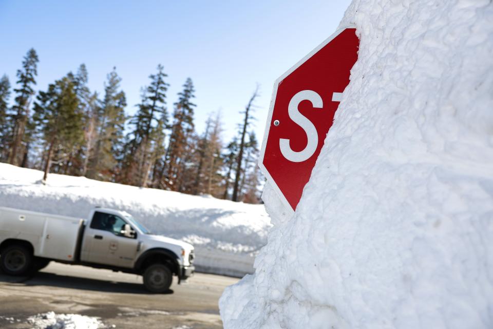 A truck passes by a stop sign that is buried in snow on March 3, 2023 in Twin Bridges, California. A Sierra snowpack survey conducted revealed a recorded snow depth of 116.5 inches and a snow water equivalent of 41.5 inches, which is 177 percent of average for this location.