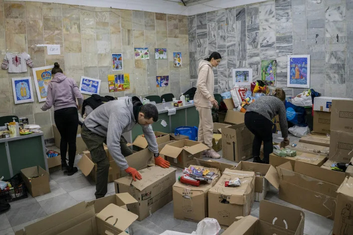 Several volunteers sort through boxes of food donations at a distribution center. 