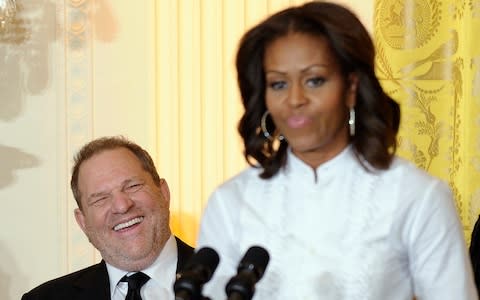 Movie mogul Harvey Weinstein, left, smiles as first lady Michelle Obama speaks in the East Room of the White House  - Credit: AP