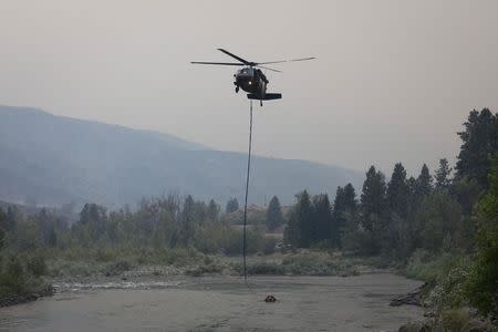 A helicopter gathers water from the Methow River to battle the Carlton Complex Fire near Methow, Washington July 18, 2014. REUTERS/David Ryder