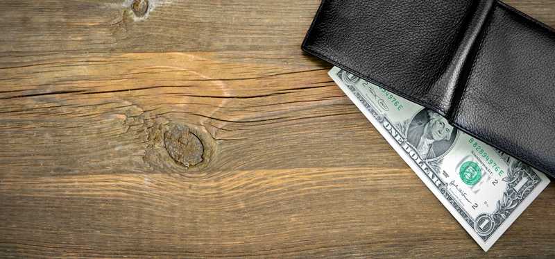 A one dollar bill in a wallet on a table.