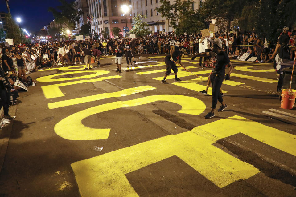 Demonstrators paint the words 'defund the police' as they protest Saturday, June 6, 2020, near the White House in Washington, over the death of George Floyd, a black man who was in police custody in Minneapolis. Floyd died after being restrained by Minneapolis police officers. (AP Photo/Jacquelyn Martin)