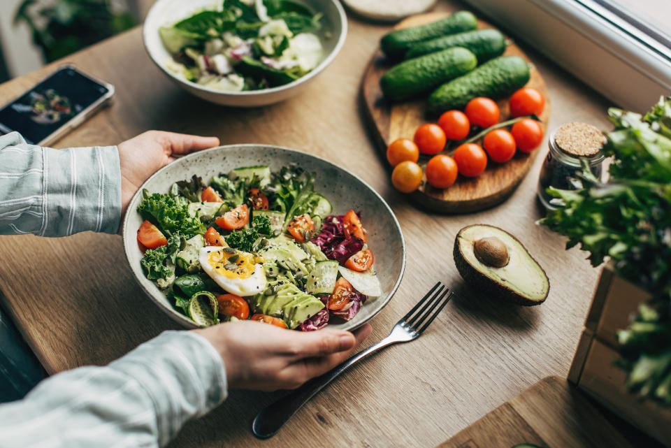 Woman mixing healthy ingredients with wooden spoons in kitchen. (Getty Images)