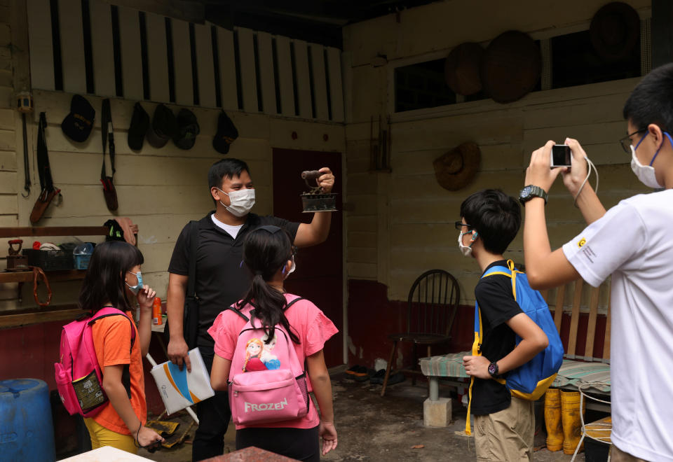 Local tour guide Kyanta Yap shows a traditional clothes iron in Kampong Lorong Buangkok, the last remaining village in Singapore October 3, 2020. Picture taken October 3, 2020.  REUTERS/Edgar Su