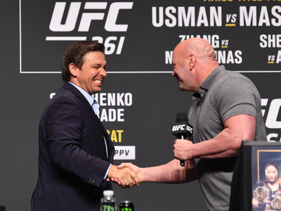 Florida Gov. Ron DeSantis grimaces while shaking hands during an event to promote a UFC fight in Jacksonville in April 2021.