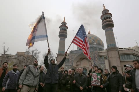 Iranians in Tehran burn an Israeli and a US flag during an anti-US protest over the killings during a US air strike of Iranian military commander Qassem Soleimani  - Credit: AFP