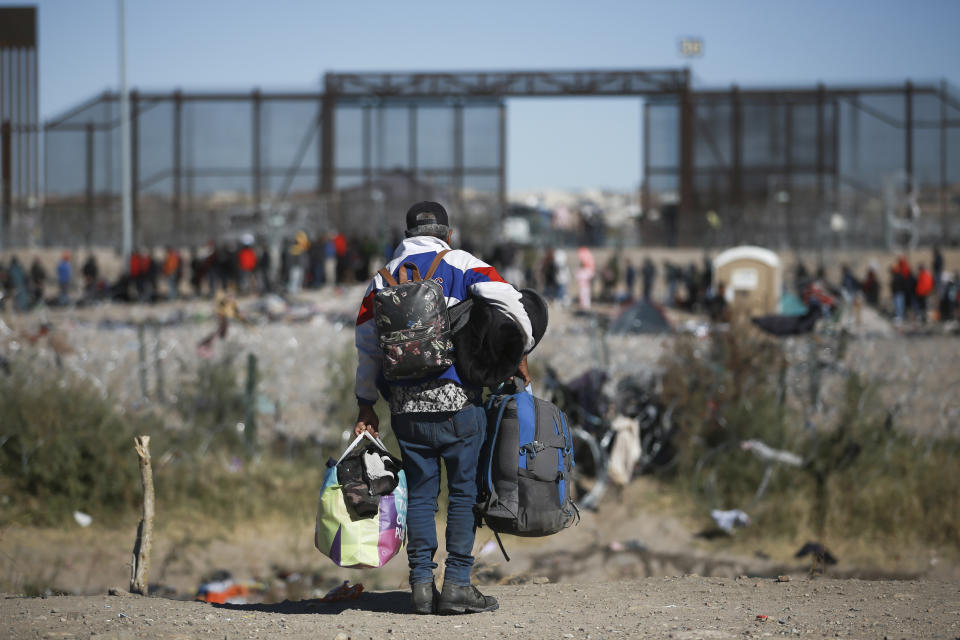 A migrants carries bags towards the U.S. border fence from Ciudad Juarez, Mexico, Wednesday, Dec. 27, 2023. (AP Photo/Christian Chavez)