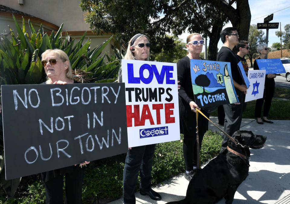 FILE - People gathering on a street corner hold signs in support of the victims of the Chabad of Poway synagogue shooting, Sunday, April 28, 2019, in Poway, Calif. A man opened fire the previous day inside the synagogue near San Diego as worshippers celebrated the last day of a major Jewish holiday. (AP Photo/Denis Poroy, File)