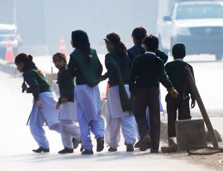 Schoolchildren cross a road as they move away from a military run school that is under attack by Taliban gunmen in Peshawar, December 16, 2014. REUTERS/Khuram Parvez