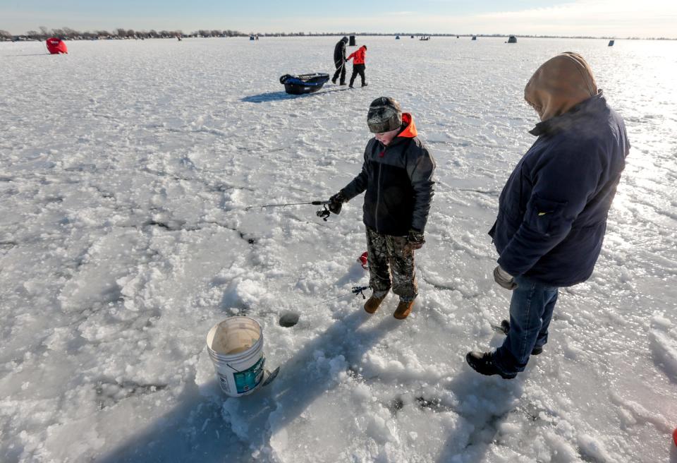 Dakota Rinehart, of Port Huron, looks through ice at his spot on the frozen Lake St. Clair in Ira Township while ice fishing with his grandfather Ray Rinehart, of Port Huron, on Thursday, Dec. 28, 2017.