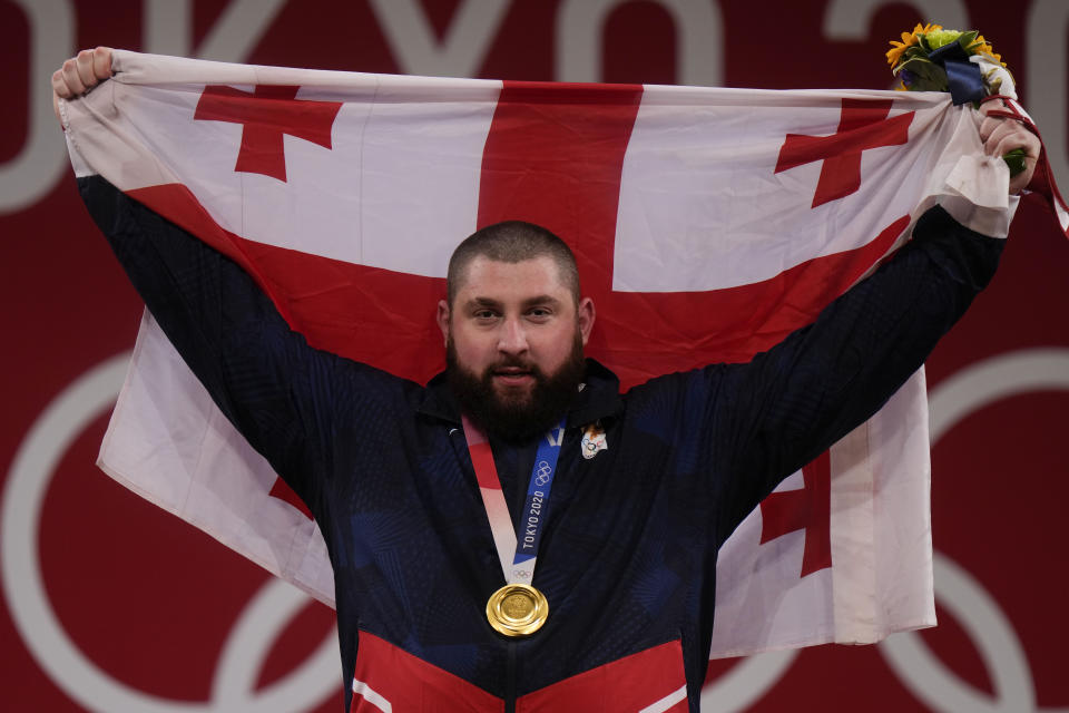 Lasha Talakhadze of Georgia holds his national flag as he celebrates the gold medal he won at the men's +109kg weightlifting event, at the 2020 Summer Olympics, Wednesday, Aug. 4, 2021, in Tokyo, Japan.(AP Photo/Luca Bruno)