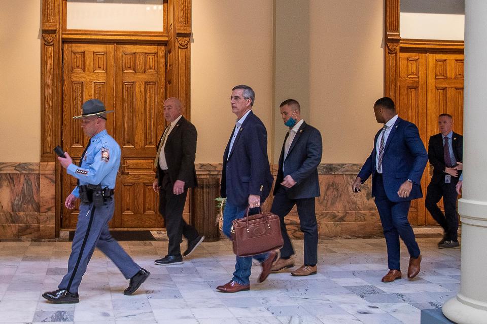 Lead by a Georgia State Trooper, Georgia Secretary of State Brad Raffensperger, center, exits the Georgia State Capitol building after hearing reports of threats, in Atlanta, Jan. 6, 2021.<span class="copyright">Alyssa Pointer—Atlanta Journal-Constitution/AP</span>