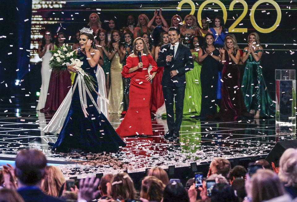 FILE - Virginia's Camille Schrier, left, walks the stage after winning the Miss America competition at the Mohegan Sun casino in Uncasville, Conn., Dec. 19, 2019. The Miss America competition is marking its 100th anniversary on Thursday, Dec. 16, 2021, managing to maintain a complicated spot in American culture. With viewership down, the event now held at the Mohegan Sun casino in southeastern Connecticut, is moving from broadcast television to NBC's streaming Peacock service this year. (AP Photo/Charles Krupa, File)