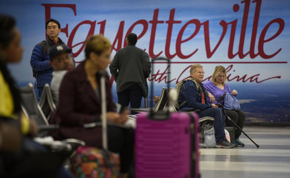 Travelers wait at the baggage claim area after a flight at Fayetteville Regional Airport in March 2021. The airport offers domestic and international flights, with some costing less than $215 between July and September.
