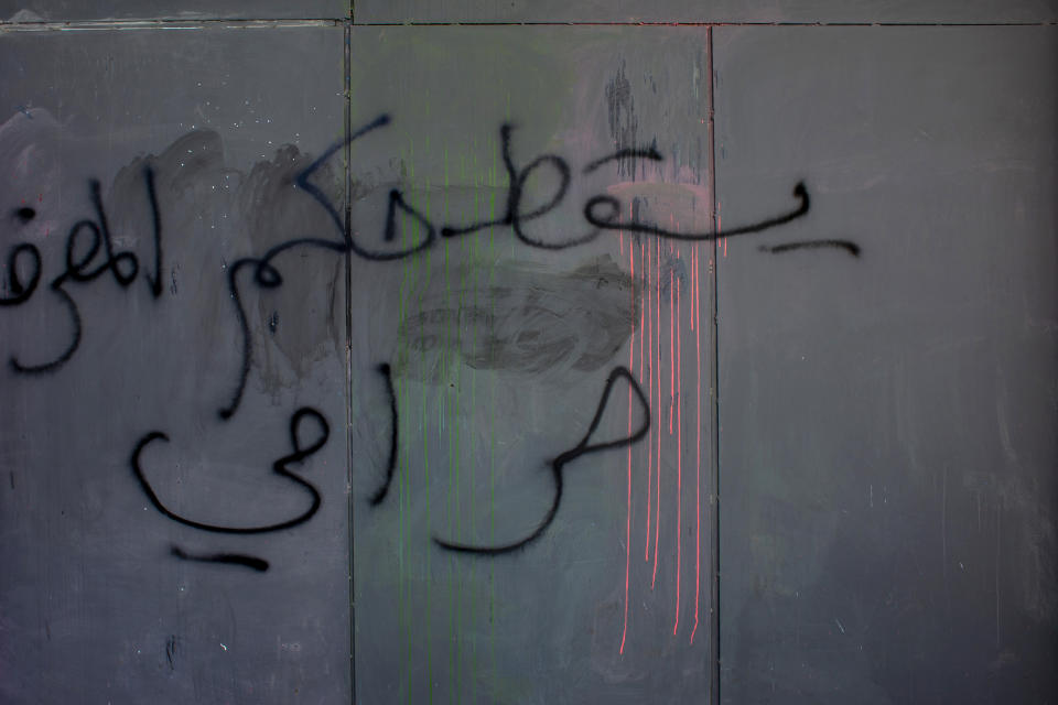 In this Sunday, May 17, 2020 photo, graffiti referring to Riad Salameh, Lebanon’s long-serving central bank governor, reads in Arabic, "Down with the rule of the bank robber," on iron shields covering the facade of a bank to prevent acts of sabotage, in Beirut, Lebanon. Salameh was touted as the guardian of Lebanon’s monetary stability as he steered the tiny country's finances through post-war recovery and various bouts of unrest for nearly three decades. Now he is being called a “thief” by some protesters, who accuse him of being part of the ruling elite whose corruption and mismanagement has driven the country to the edge of bankruptcy. (AP Photo/Hassan Ammar)