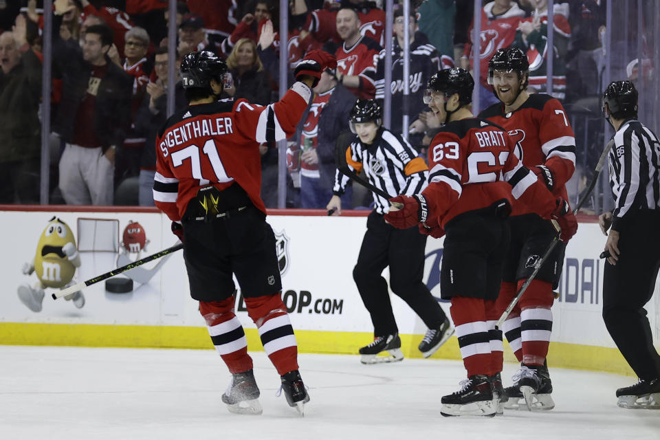 New Jersey Devils left wing Jesper Bratt (63) celebrates after scoring a goal with Jonas Siegenthaler (71) and Dougie Hamilton against the Carolina Hurricanes during the first period of an NHL hockey game, Sunday, March 12, 2023, in Newark, N.J. (AP Photo/Adam Hunger)