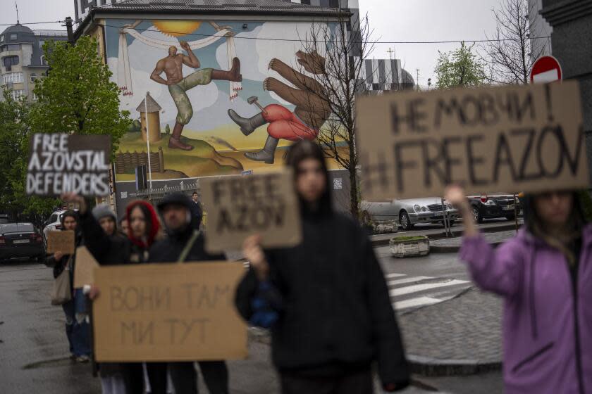 People stand in front of a mural symbolising Ukraine's fight against Russia as they attend a rally aiming to raise awareness on the fate of Ukrainian prisoners of war, in Kyiv, Ukraine, Sunday, April 21, 2024. The U.S. House of Representatives swiftly approved $95 billion in foreign aid for Ukraine, Israel and other U.S. allies in a rare Saturday session as Democrats and Republicans banded together after months of hard-right resistance over renewed American support for repelling Russia's invasion. (AP Photo/Francisco Seco)