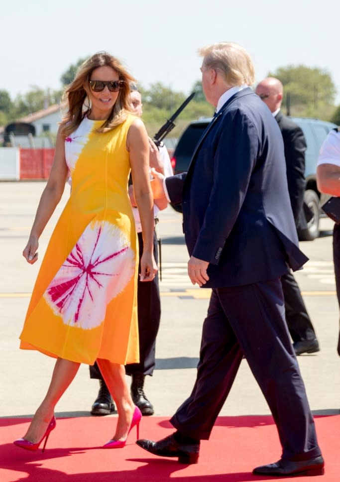 Melania Trump shows off a mango printed dress with hot pink patent Christian Louboutin heels in France. - Credit: Shutterstock