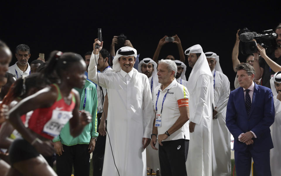 Emir of Qatar Sheikh Tamim bin Hamad Al Thani fires the starting pistol to get the women's marathon underway at the World Athletics Championships as IAAF President Sebastian Coe, right, looks on in Doha, Qatar, Saturday, Sept. 28, 2019. (AP Photo/Hassan Ammar)