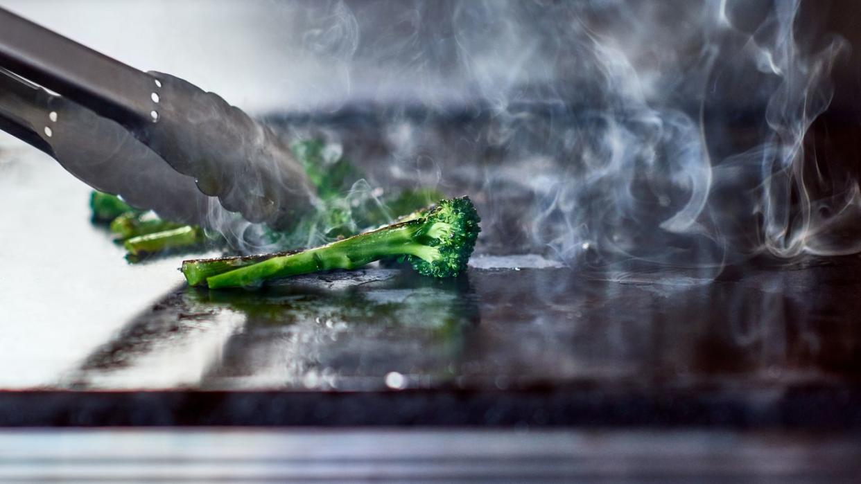 tongues turning fresh broccoli on hot plate