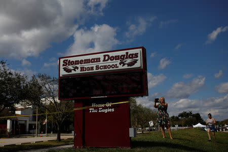 People take pictures in front of the Marjory Stoneman Douglas High School, following a mass shooting in Parkland, Florida, U.S., February 18, 2018. REUTERS/Carlos Garcia Rawlins
