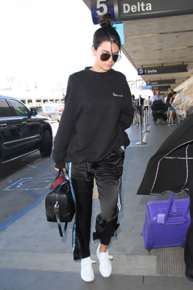 <p>À l’aéroport, Kendall portait un hoodie noir Vetements et un pantalon de survêtement noir à bandes bleues. (Photo : Getty) </p>