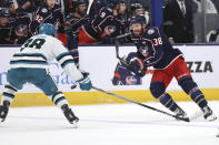 Columbus Blue Jackets forward Boone Jenner, right, passes the puck in front of San Jose Sharks defenseman Mario Ferraro during the second period of an NHL hockey game in Columbus, Ohio, Saturday, March 16, 2024. (AP Photo/Paul Vernon)
