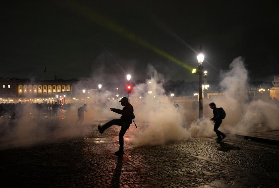 Demonstrators run through the tear gas during a protest in Paris on Friday (AP)