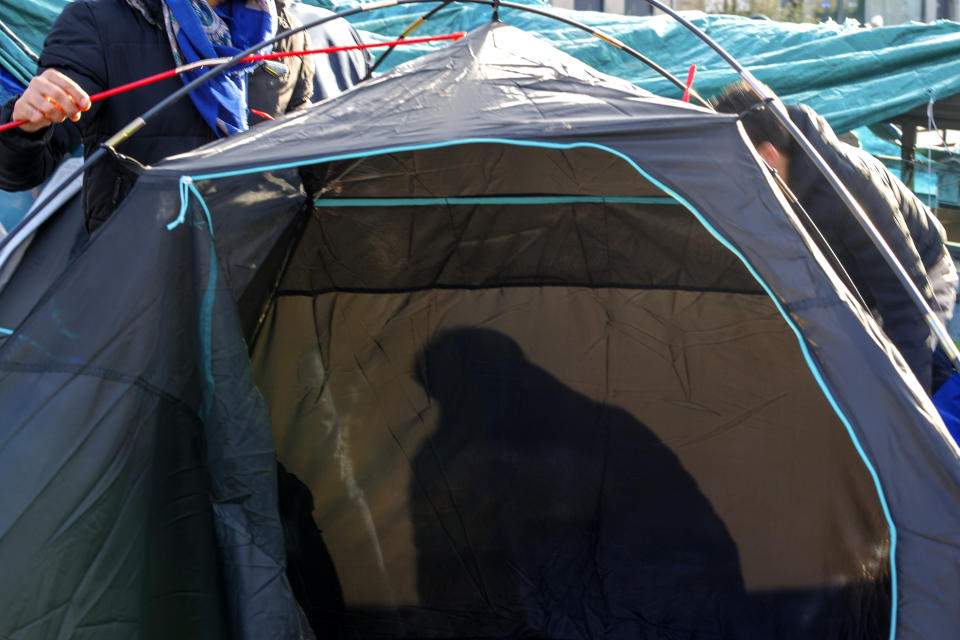 A man sits inside of a tent in a makeshift camp outside the Petit Chateau reception center in Brussels, Tuesday, Jan. 17, 2023. Many refugees and asylum-seekers are literally left out in the cold for months as the European Union fails to get its migration system working properly. And most talk is about building fences and repatriation instead of working to improve a warm embrace for people fleeing nations like Afghanistan where the Taliban has taken over. (AP Photo/Olivier Matthys)