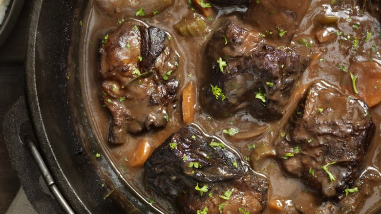 Top-down view of beef short rib stew in a cast iron skillet