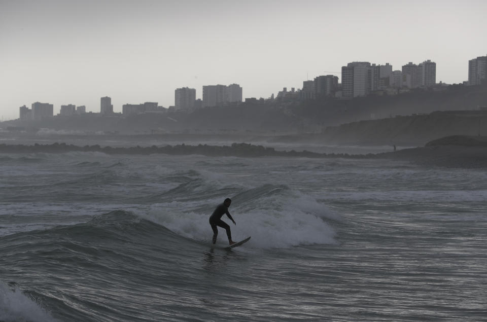 A surfer rides a wave off the coast of Lima, Peru, as darkness falls Thursday, July 25, 2019. Today, dozens of schools teach tourists from across the world how to ride waves at beaches with Hawaiian names in Lima's Miraflores district, while professional surfers from across the Americas prepare to compete when the sport is featured for the first time in the Pan American Games in the Peruvian capital.(AP Photo/Rebecca Blackwell)