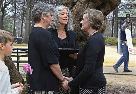 A protester waving a bible walks past as two women named Donna and Tina get married in a park outside the Jefferson County Courthouse in Birmingham, Alabama, in this file photo taken February 9, 2015. REUTERS/Marvin Gentry/Files