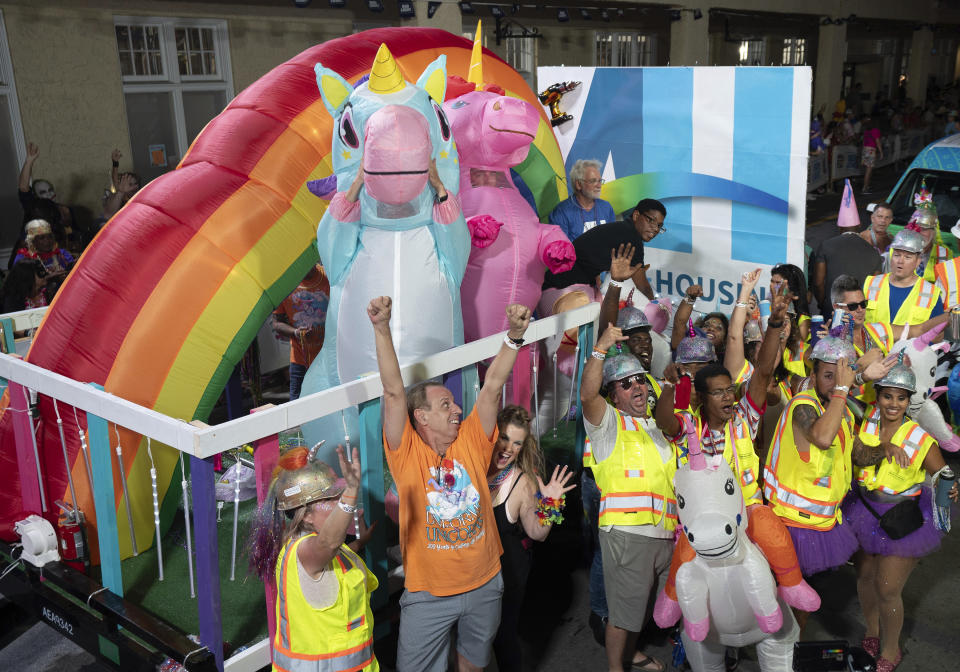 In this Saturday, Oct. 28, 2023, photo provided by the Florida Keys News Bureau, a large-scale unicorn duo presides over a crew of costumed "construction workers" during the Fantasy Fest Parade in Key West, Fla. Attracting tens of thousands of spectators, the elaborate procession highlighted subtropical island's 10-day Fantasy Fest costuming and masking festival that ends Sunday, Oct. 29. (Rob O'Neal/Florida Keys News Bureau via AP)