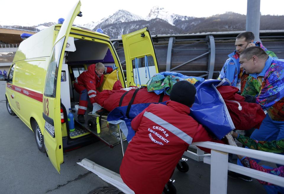 A track worker is loaded into an ambulance after he was injured when a forerunner bobsled hit him just before the start of the men's two-man bobsled training at the 2014 Winter Olympics, Thursday, Feb. 13, 2014, in Krasnaya Polyana, Russia. (AP Photo/Charlie Riedel)