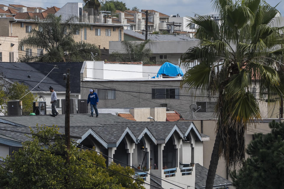 Workers check the roof of an apartment ahead of forecasted rain in Los Angeles, Sunday, Feb. 18, 2024. (AP Photo/Damian Dovarganes)